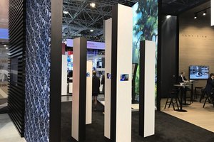 Moderne Messestand-Konstruktion mit vertikalen Banner-Displays und Besuchern im Hintergrund