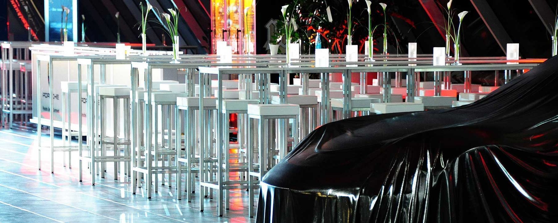 Ein eleganter Veranstaltungsraum mit Tischen, Stühlen und einem bedeckten Objekt.