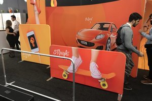Messestand mit bunten, bedruckten Display-Systemen, inklusive Popup-Bannern und Standwänden mit lebensgrossen Produktabbildungen und Besuchern im Gespräch.