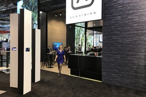 Modern gestalteter Messestand mit einer Person, Markenlogo und Besuchern im Hintergrund