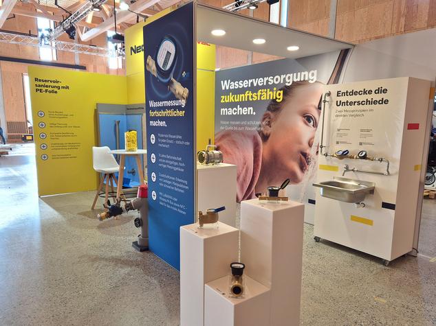 Ein Messestand für Wassertechnik mit verschiedenen Wasserzählern und einem Waschbecken.