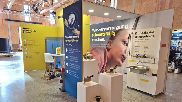 Ein Messestand für Wassertechnik mit verschiedenen Wasserzählern und einem Waschbecken.