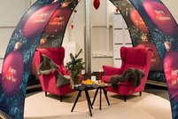 Festlich dekorierter Messestand mit Weihnachtsthema, Sesseln und Beistelltisch