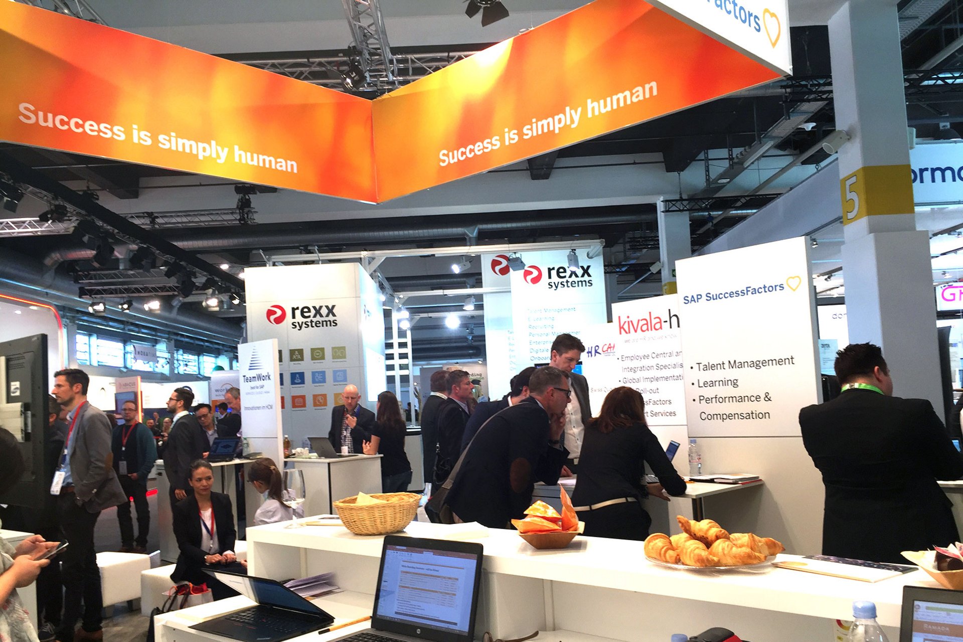 Geschäftiges Messeambiente mit verschiedenen Ausstellungsständen und Besuchern