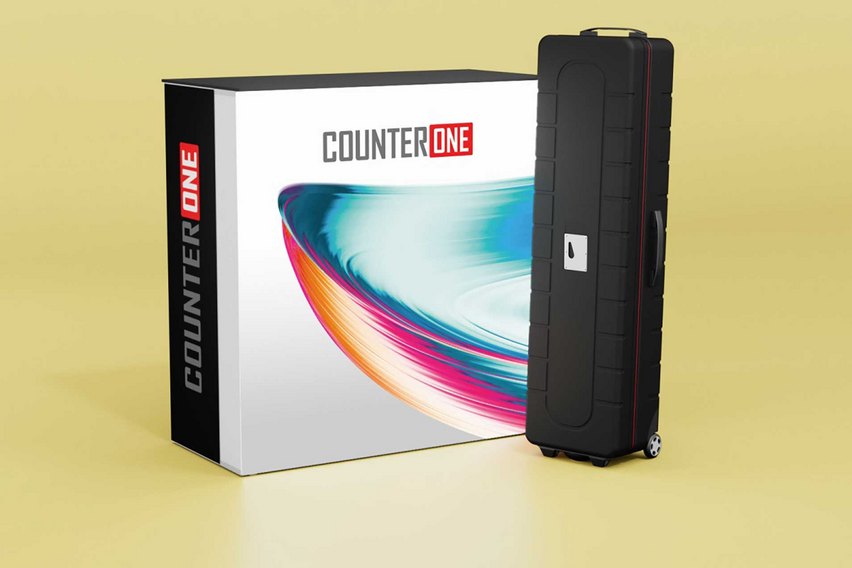 Ein schwarzer Koffer neben einer Verpackung mit dem Schriftzug "COUNTER ONE".