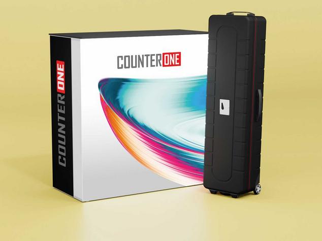 Ein schwarzer Koffer neben einer Verpackung mit dem Schriftzug "COUNTER ONE".
