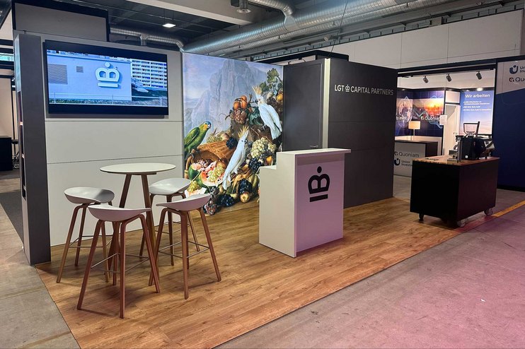 Ein Messestand mit Stehtischen, einer Theke und einer grossen Wandmalerei.