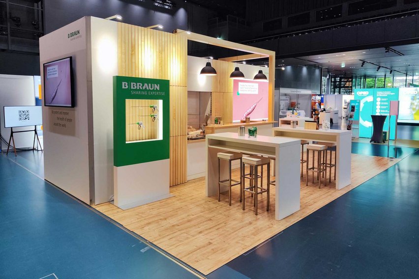 Ein Messestand mit einer Kaffeebar, Sitzgelegenheiten und digitalen Displays.