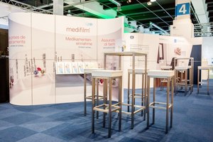 Professionell gestalteter Messestand mit Informationsdisplays und Stehtischen