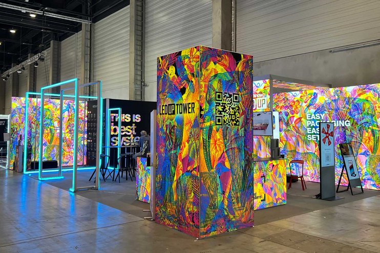 Ein bunt gestalteter Messestand mit verschiedenen Technologien und Werbematerialien.