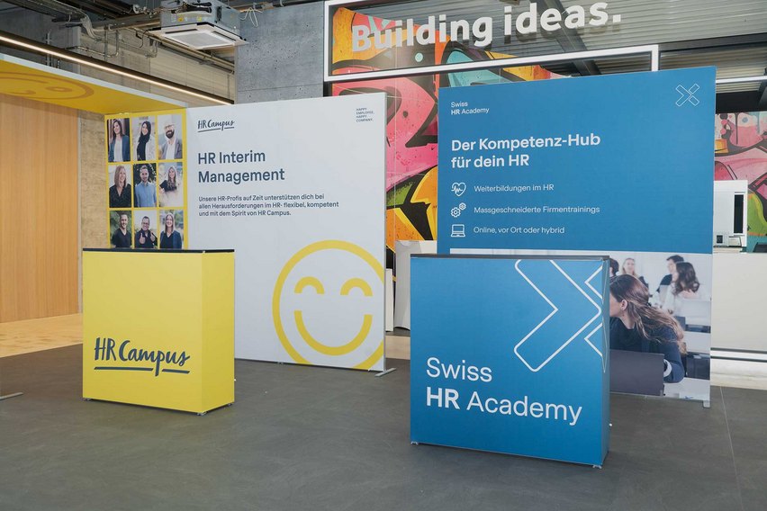 Messestand mit Informationsständen zu HR-Dienstleistungen.