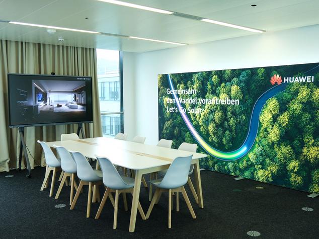 Besprechungsraum mit Tisch, Stühlen, Bildschirm und Werbebanner.