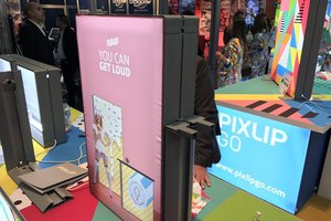 Besucher an einem farbenfrohen Messestand mit leuchtenden Displays und bedruckten Popup-Bannern