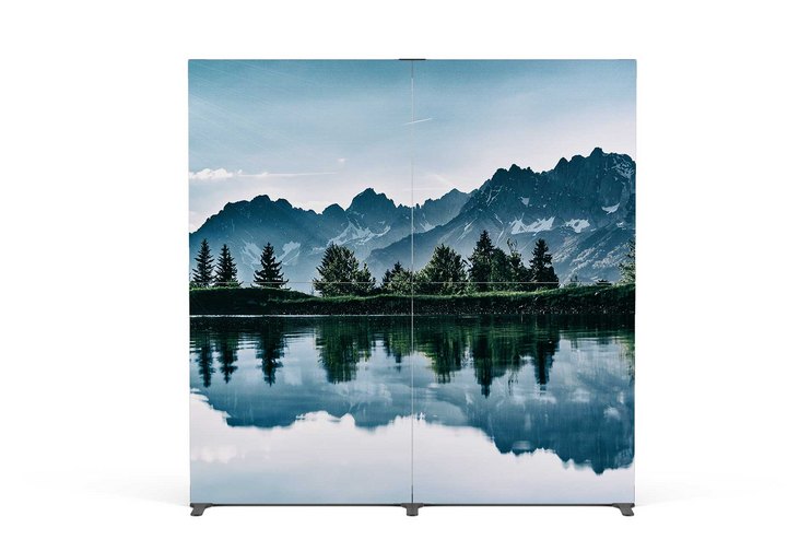 Eine Berglandschaft mit einem stillen See und Bäumen im Vordergrund.