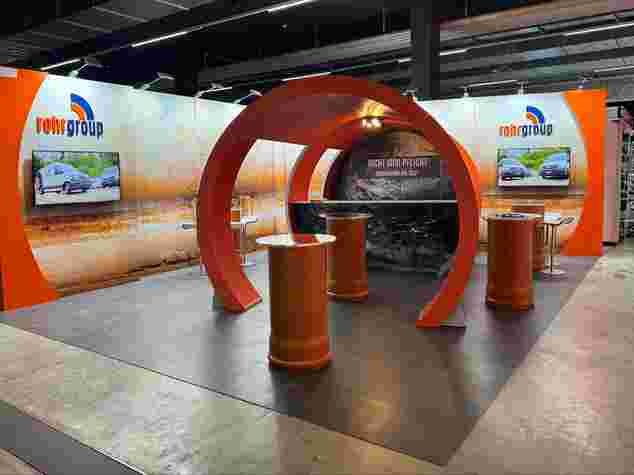 Messestand mit ovalem Designelement und Bildschirmen.