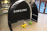 Ein schwarzes Popup-Display mit Samsung-Branding vor einer Bücherwand in einer Ausstellung.