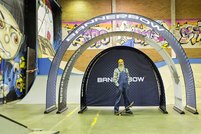 Person steht vor zusammengebautem, torbogenförmigem Messestand mit Skaterhintergrund