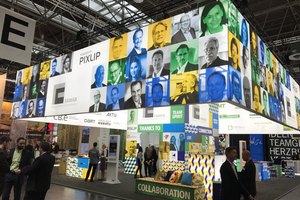Lebhafter Messestand mit beleuchteten Porträtfotos und Werbebotschaften
