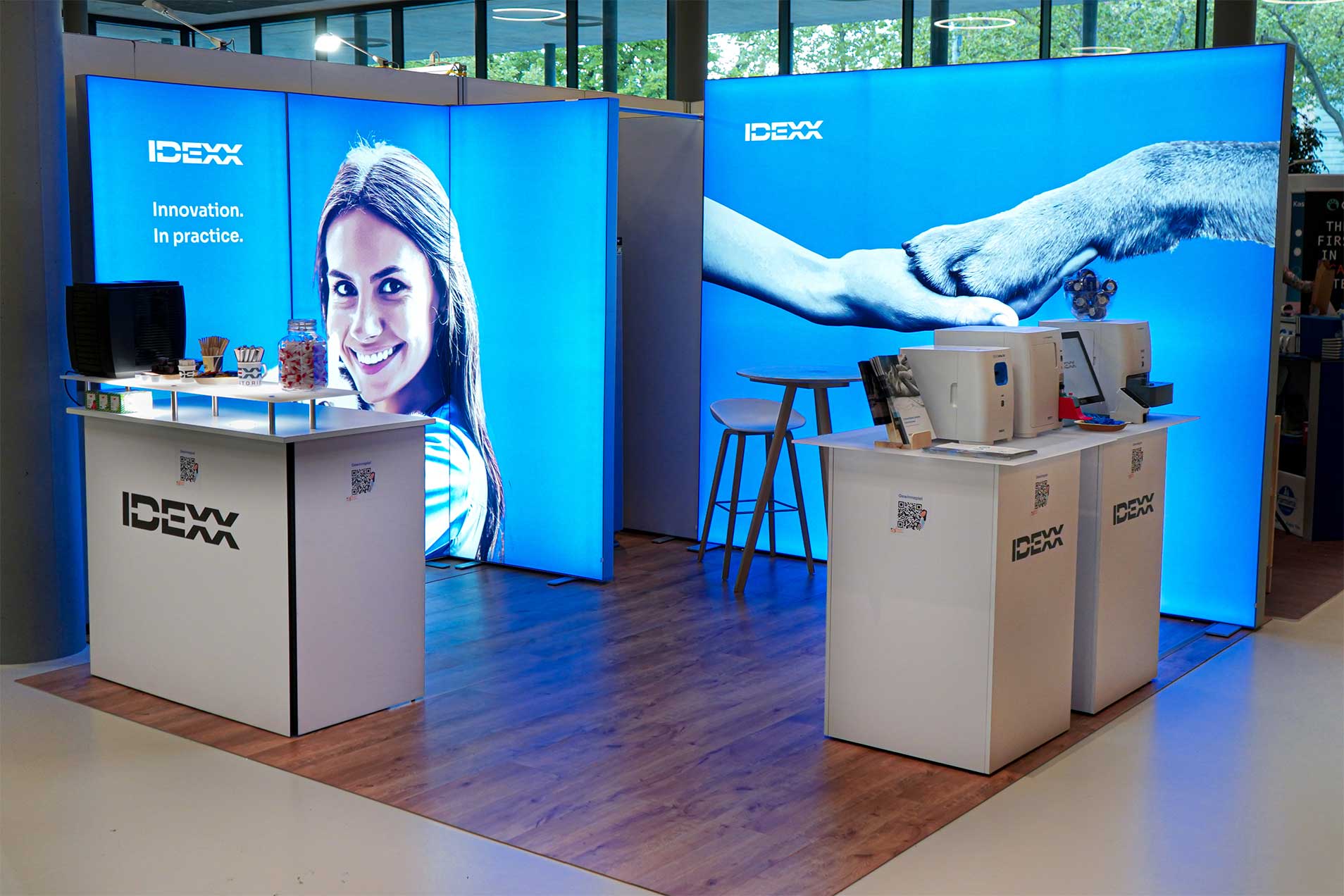 Ein Messestand mit hellblauen Wandpaneelen, einem Theke und Produkten.