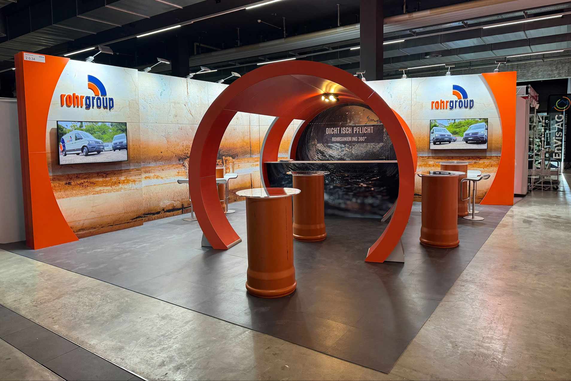 Messestand mit ovalem Designelement und Bildschirmen.